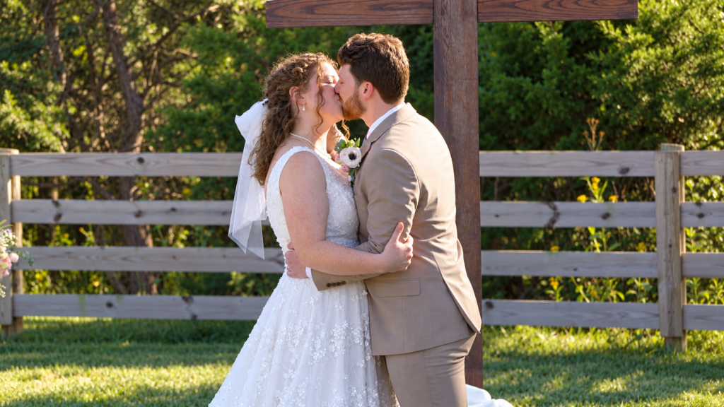 Kelly and Thomas share their first kiss during their outdoor wedding ceremony at The Barn at Spring Rose Farm in Bedford, Virginia.