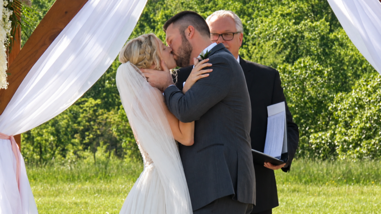 Bride and groom sharing their first kiss during an outdoor wedding ceremony in Virginia