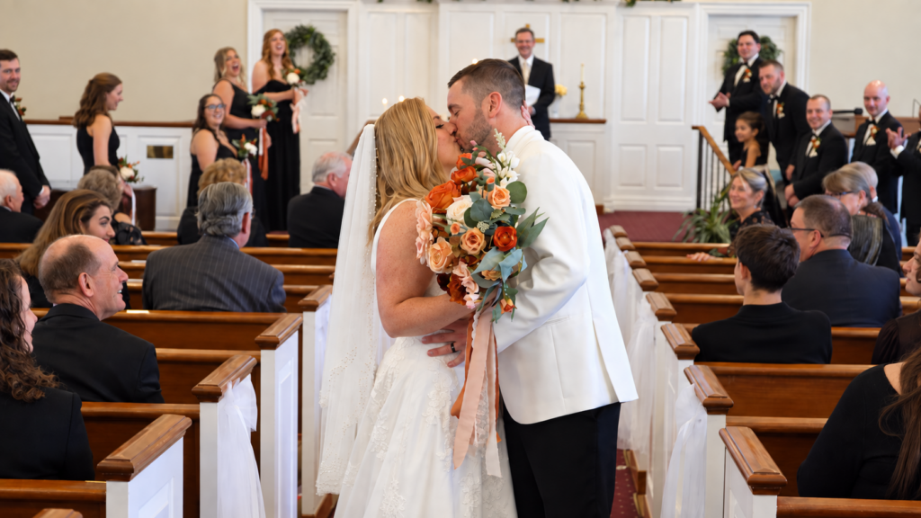 Bride and groom share a kiss in the aisle after their wedding ceremony